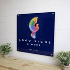 Metal logo sign featuring a colorful bird design on a dark blue background, mounted on a white brick wall, showcasing vibrant colors and durable metal craftsmanship.
