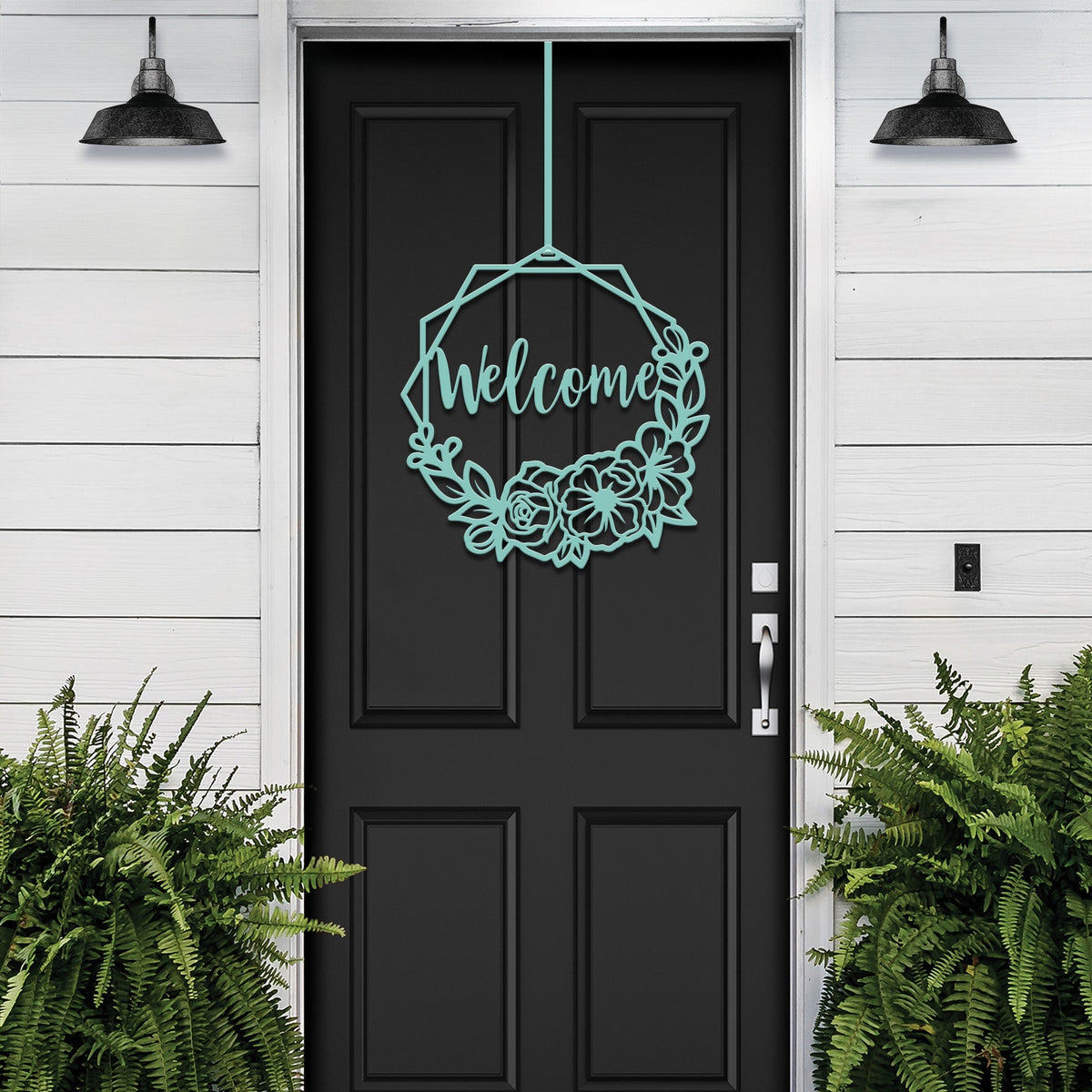 Black door with decorative “Welcome” sign on white wall with surrounding plants, custom outdoor home entrance décor