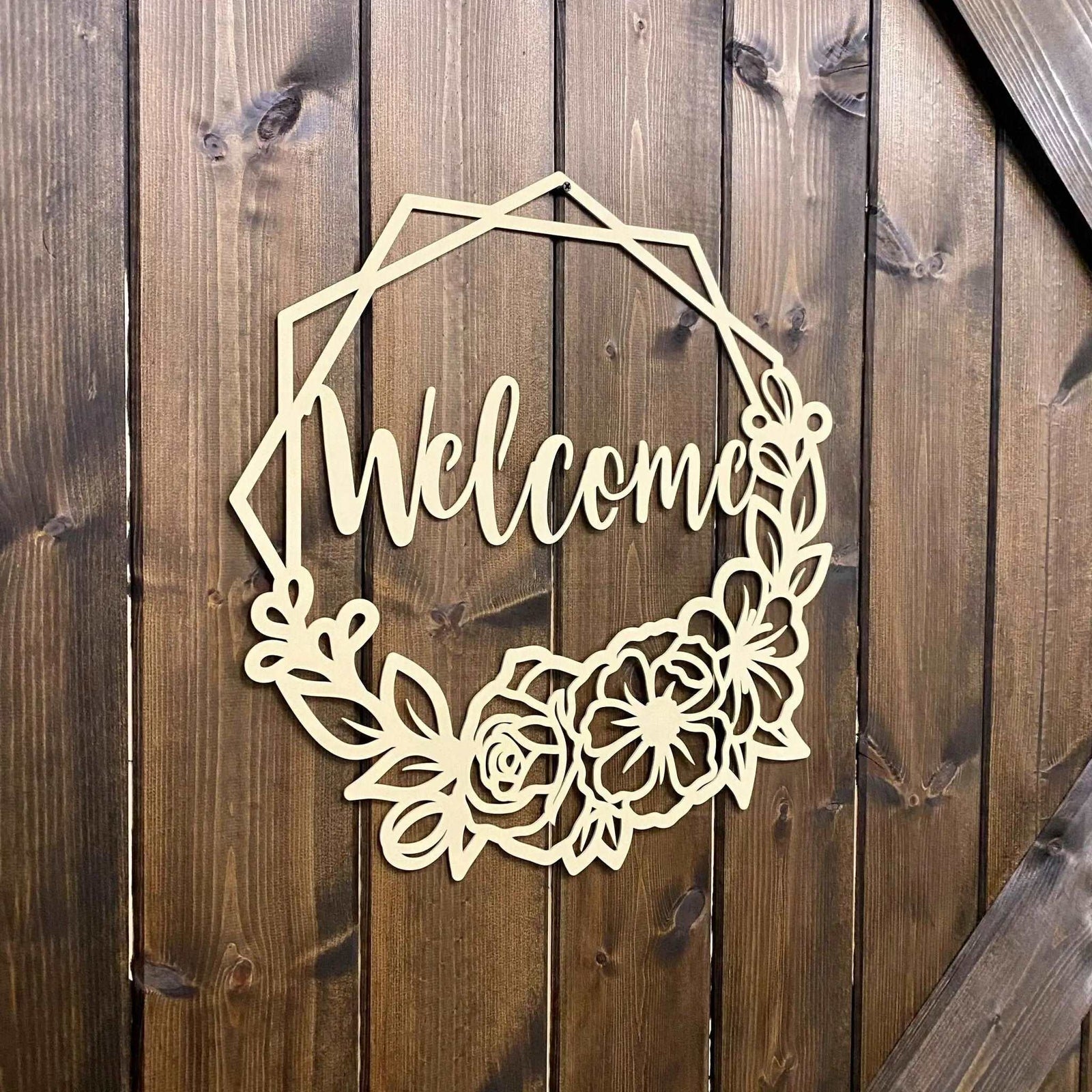 Decorative metal “Welcome” sign with floral design on wooden background, custom indoor or outdoor home décor accent