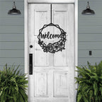 Decorative metal “Welcome” sign on white wooden door with surrounding greenery, custom outdoor home entrance décor
