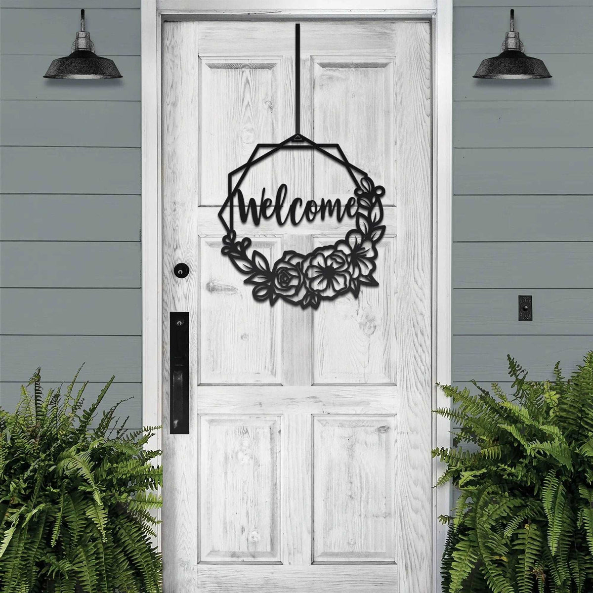 Decorative metal “Welcome” sign on white wooden door with surrounding greenery, custom outdoor home entrance décor