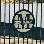 Custom metal gate sign with “MIRCHANDANI” branding, personalized family or business décor mounted on black metal gate exterior.