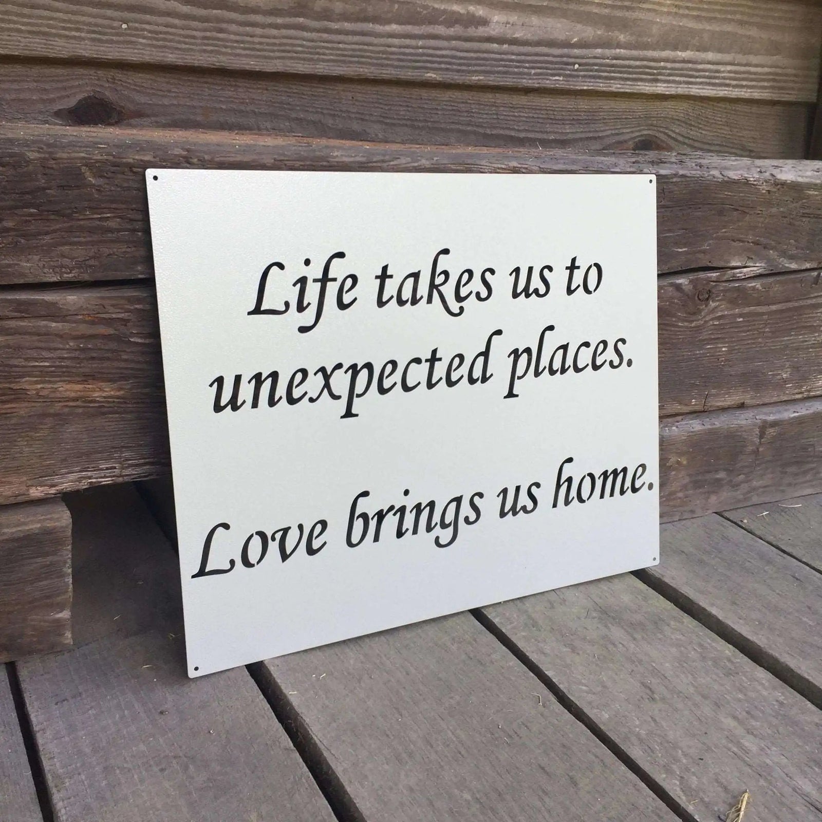 Decorative metal sign featuring a motivational quote, displayed on a wooden surface, showcasing rustic style and durable craftsmanship for home or office décor.