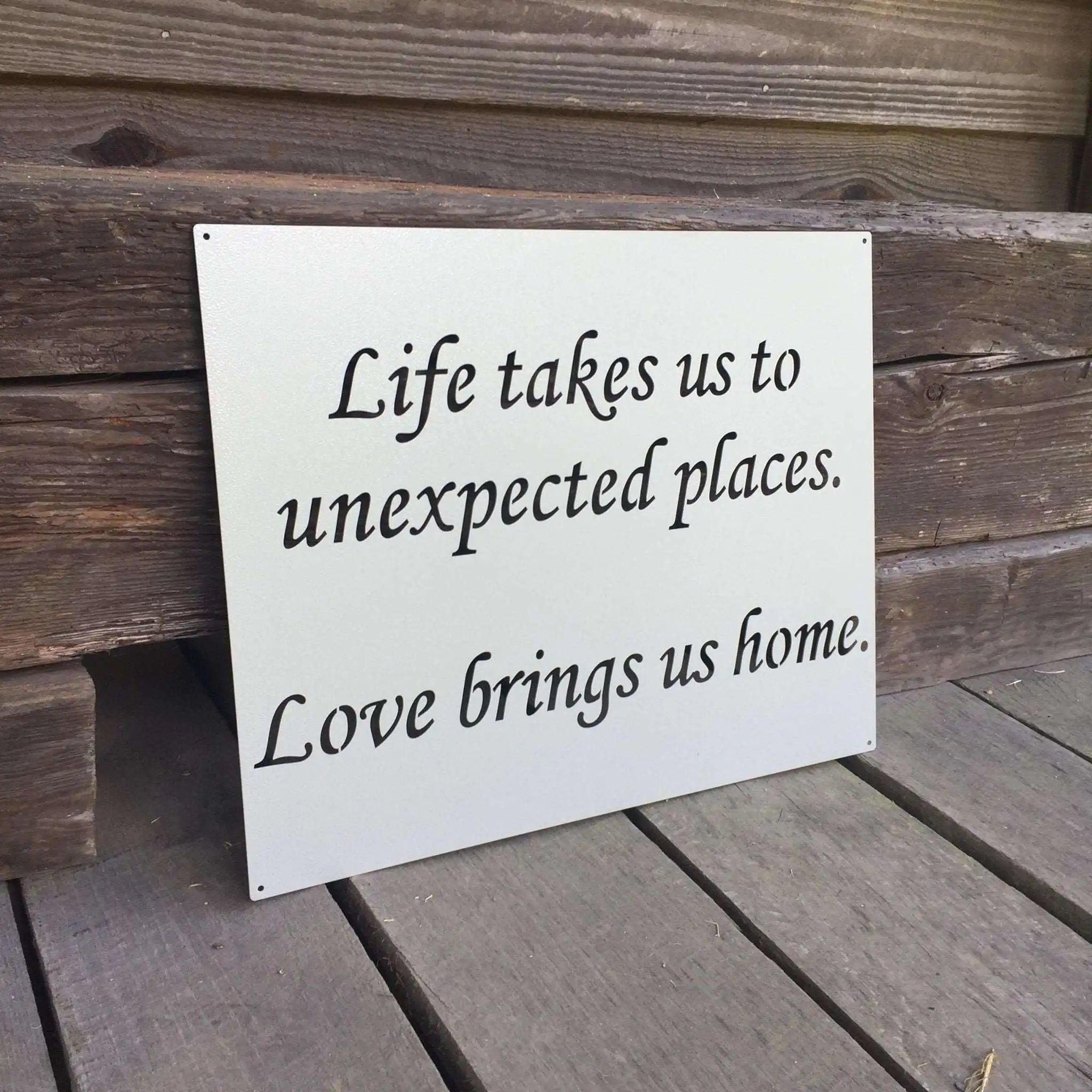 Decorative metal sign featuring a motivational quote, displayed on a wooden surface, showcasing rustic style and durable craftsmanship for home or office décor.