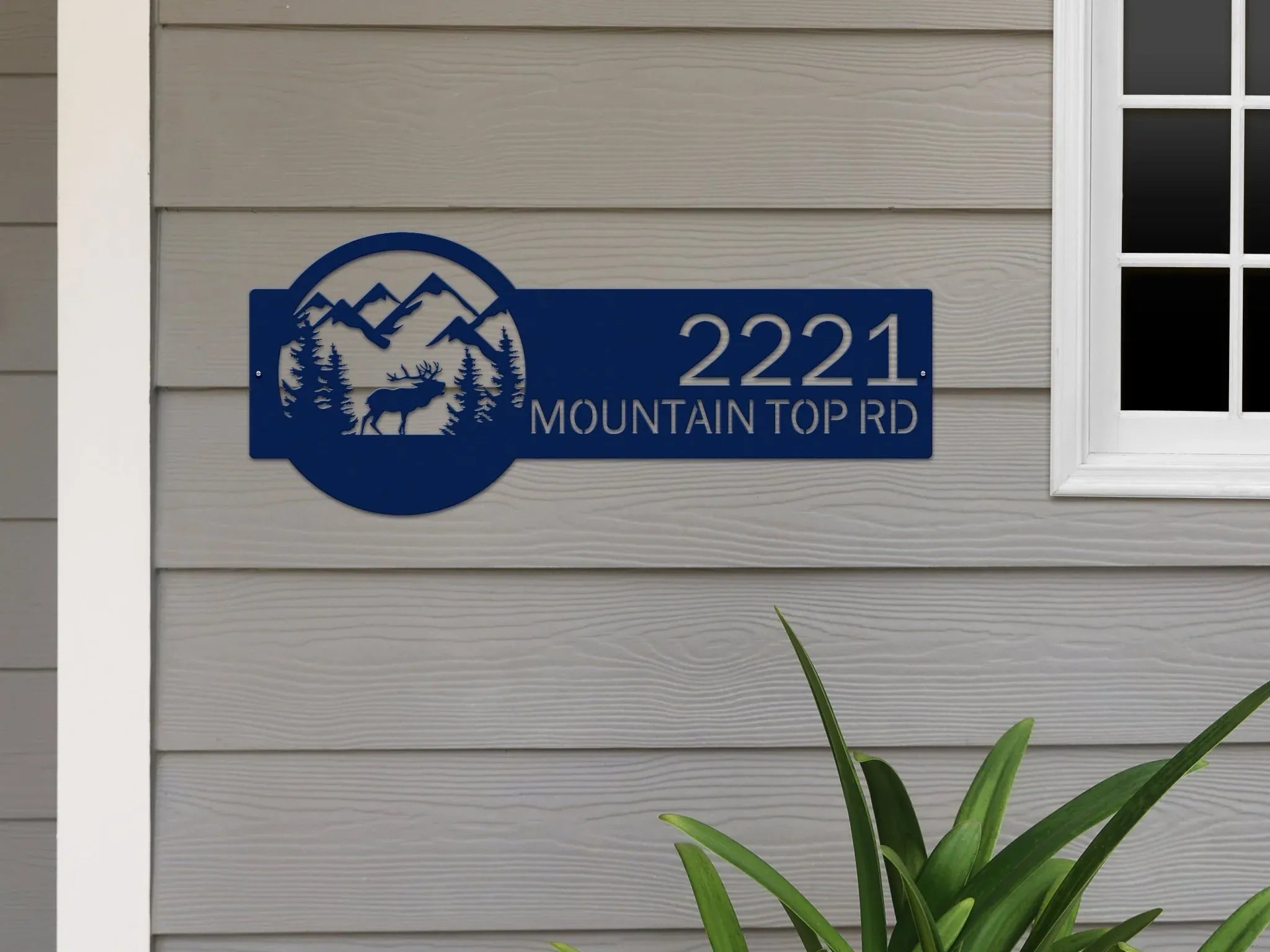 House number sign with mountain and deer design on gray siding wall, rustic outdoor moose cabin metal decor