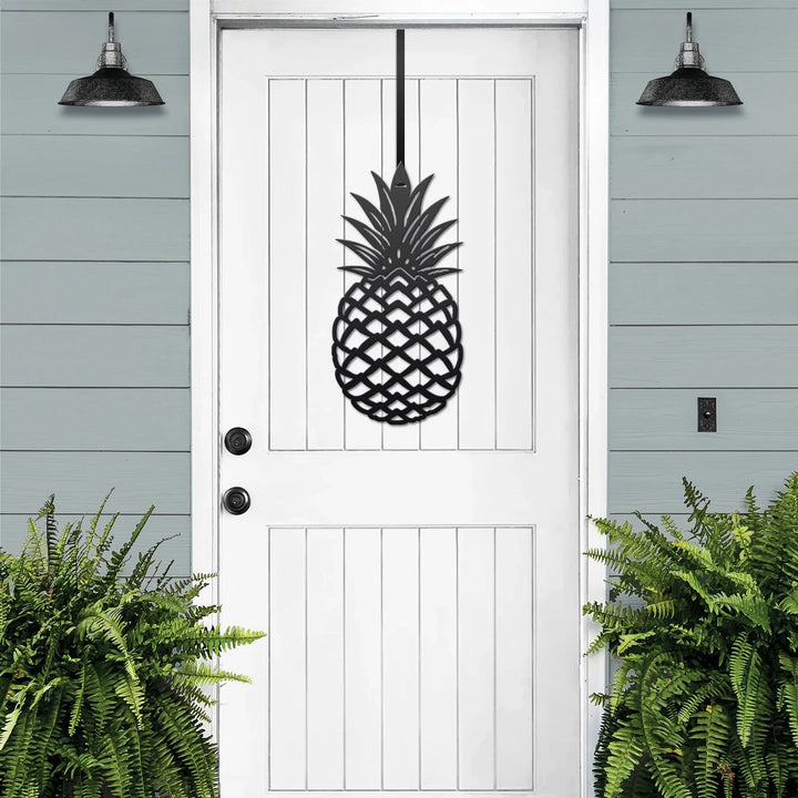 Black pineapple metal welcome wreath mounted on a white front door