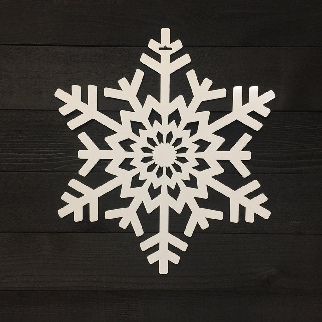 White snowflake-shaped decorative item placed on a dark wooden background, highlighting intricate detailing and festive seasonal design.