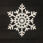White snowflake-shaped decorative item placed on a dark wooden background, highlighting intricate detailing and festive seasonal design.