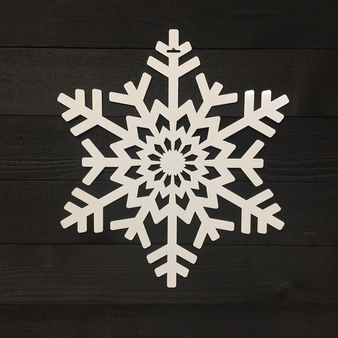 White snowflake-shaped decorative item placed on a dark wooden background, highlighting intricate detailing and festive seasonal design.