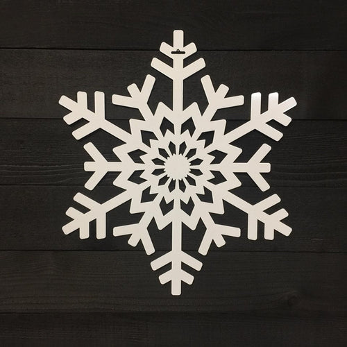 White snowflake-shaped decorative item placed on a dark wooden background, highlighting intricate detailing and festive seasonal design.