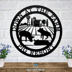 Decorative metal farm sign with pig scene and “Down at the Farm Pig Resort” text on white brick wall, front door outdoor plaque, rustic décor