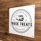 “Truck Treats” fast food truck sign on a wooden background, featuring bold, colorful lettering and a rustic, eye-catching design suitable for outdoor display.