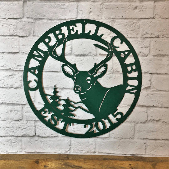 Bionic green metal sign on light brick wall with deer head, pine tree, “EST 1988” and “DANIELSON” cut into the border.