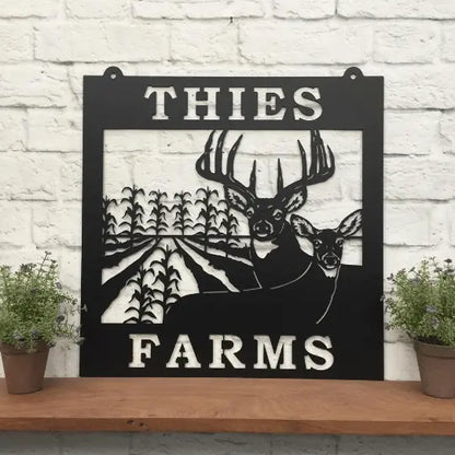 Deer & Corn Rows Farm Metal Sign displayed on a shelf, featuring a black and white deer image. Ideal for outdoor decor in gardens or farms, perfect as a housewarming gift for animal lovers.