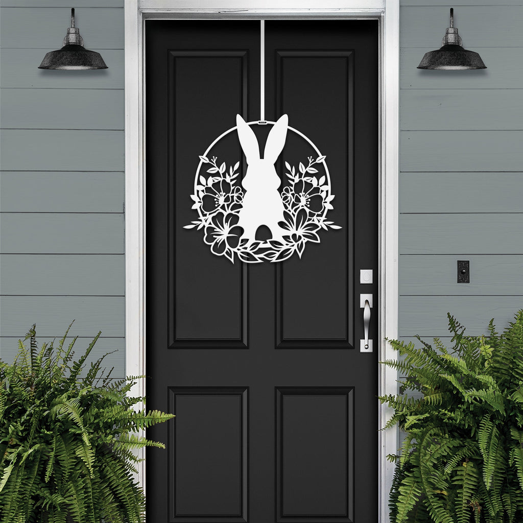 White Easter bunny metal door sign with floral wreath, custom rabbit silhouette front door décor, powder coated outdoor spring decoration, farmhouse-style Easter porch sign with greenery on black door and gray siding