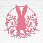 Pink Easter bunny metal wall sign with floral wreath, custom rabbit silhouette front door décor, powder coated outdoor spring decoration, farmhouse-style Easter wall art on white brick background