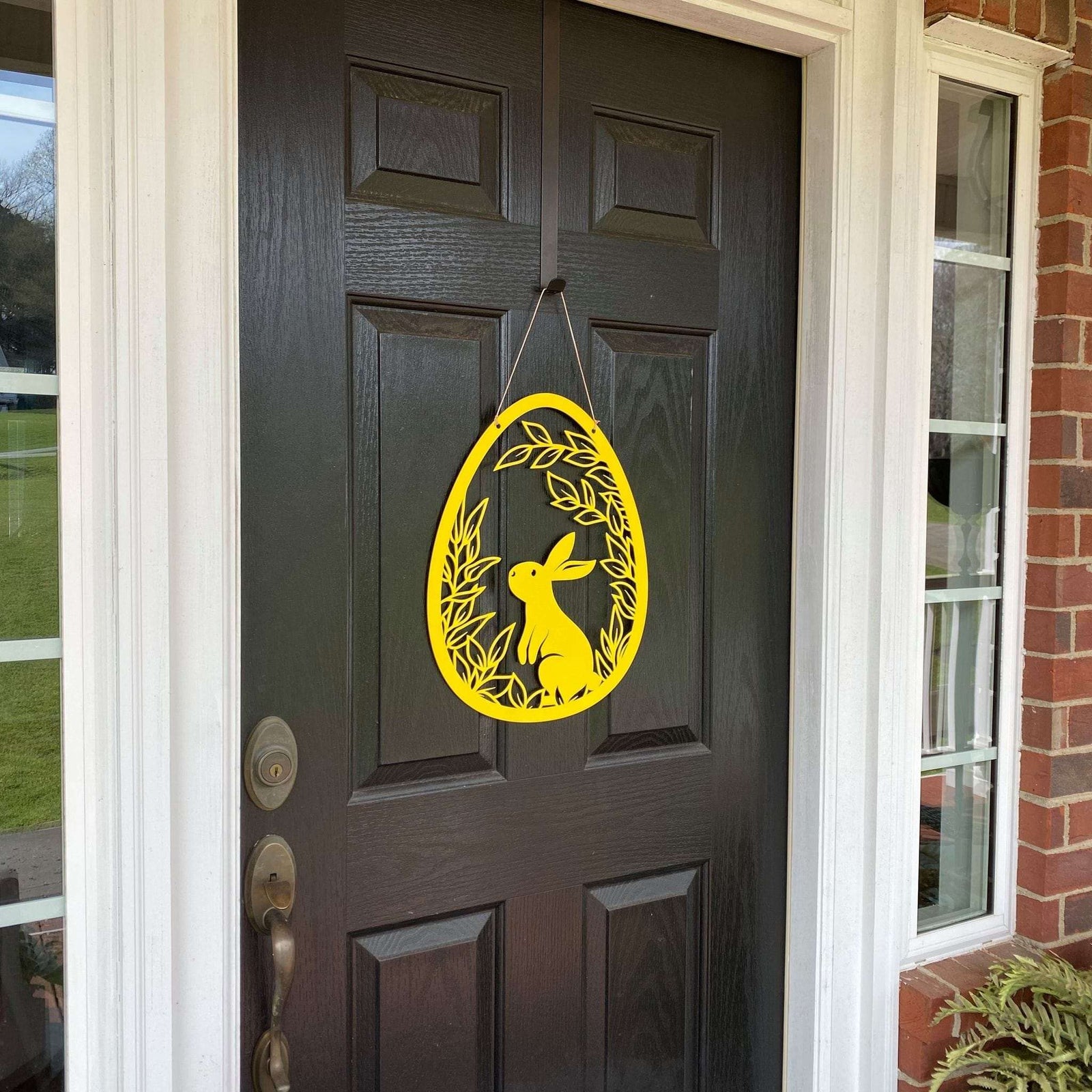 Yellow Easter egg metal door hanger with bunny design on dark brown door, custom outdoor powder coated spring décor, farmhouse Easter front door sign
