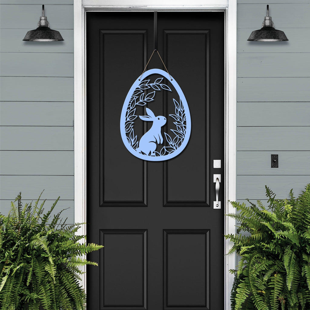 Metal Easter egg door hanger with rabbit design on black door, custom outdoor powder coated spring décor, farmhouse front door sign against gray house exterior