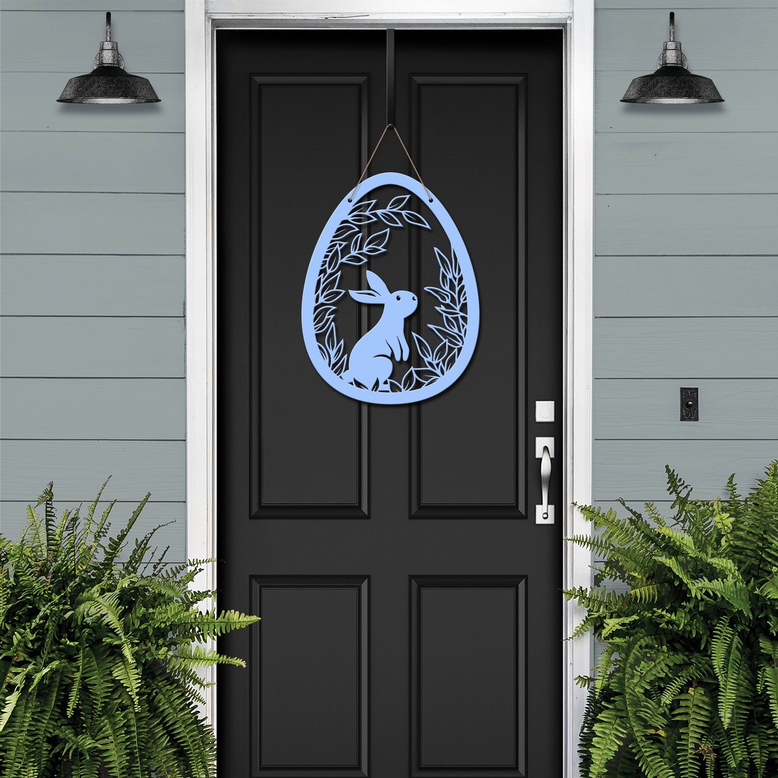 Metal Easter egg door hanger with rabbit design on black door, custom outdoor powder coated spring décor, farmhouse front door sign against gray house exterior