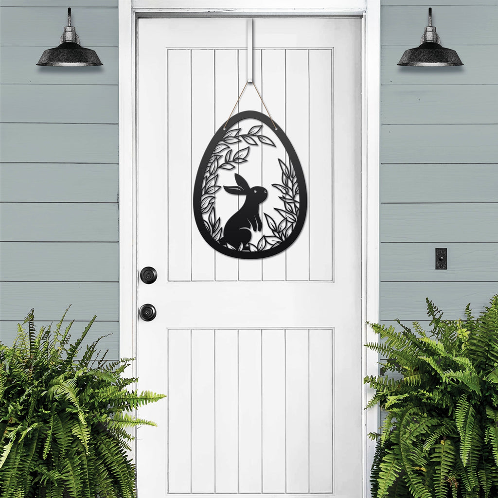 Metal Easter egg door hanger with rabbit design on white door, custom outdoor powder coated spring décor, farmhouse front door sign with greenery accents