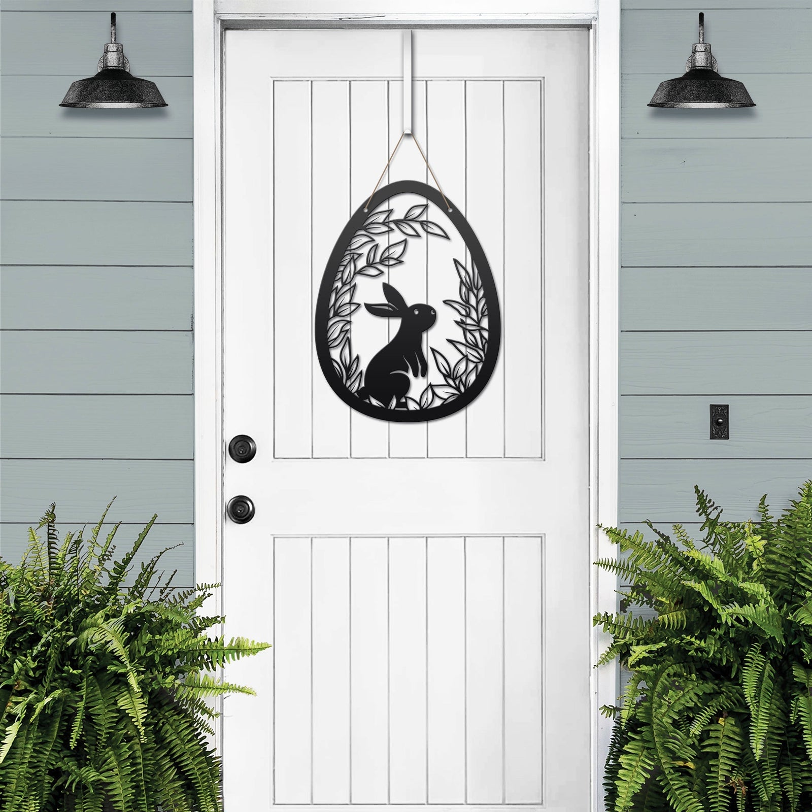 Metal Easter egg door hanger with rabbit design on white door, custom outdoor powder coated spring décor, farmhouse front door sign with greenery accents