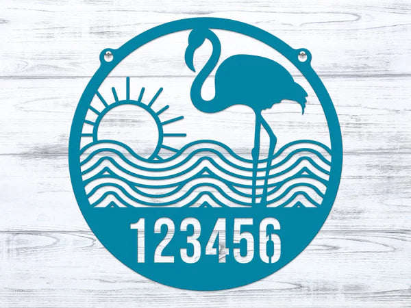 Close-up of round Turquoise Flamingo Address Sign with house number '123456', waves, and sun design.