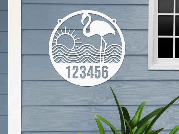 White-colored Flamingo Address Sign with house number '123456', waves, and sun design, mounted on door with gray-blue wall.