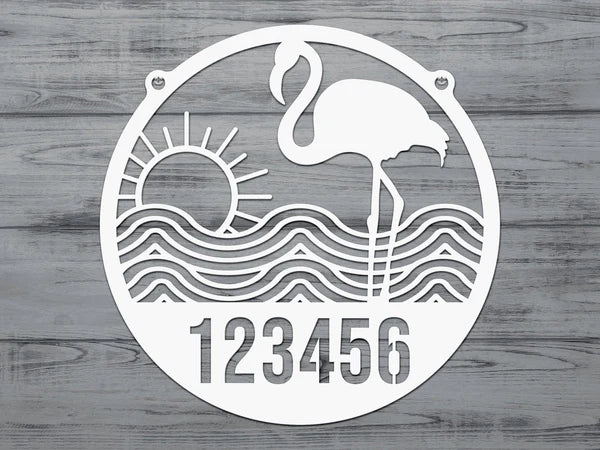 White-colored Flamingo Address Sign with house number '123456', waves, and sun design, mounted on door with gray-blue wall.