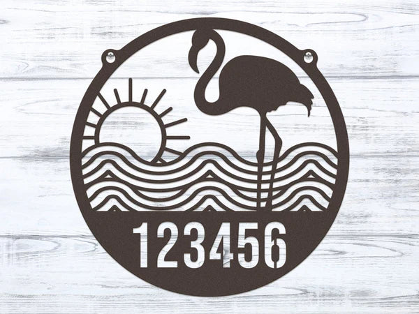 Close-up of round oil-rubbed bronze Flamingo Address Sign featuring house number '123456' with waves and sun design.