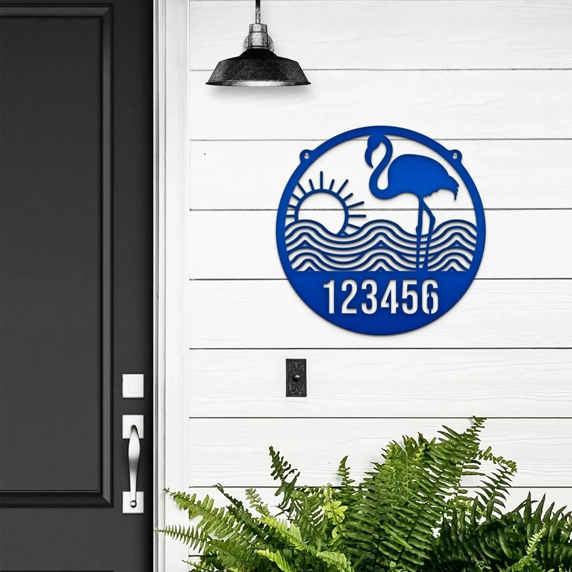 Round royal blue Flamingo Address Sign with house number '123456', flamingo, waves, and sun design, mounted on door wall.