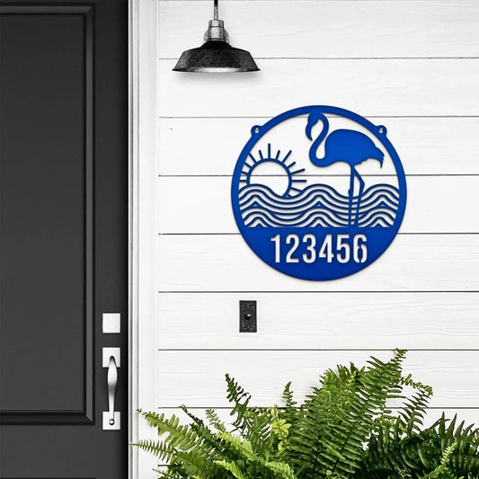 Round royal blue Flamingo Address Sign with house number '123456', flamingo, waves, and sun design, mounted on door wall.