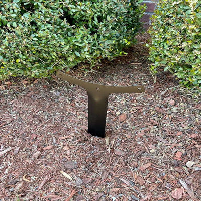 Personalized metal garden stake sign, outdoor décor anchor-style plaque installed in mulch bed with green bushes in background.