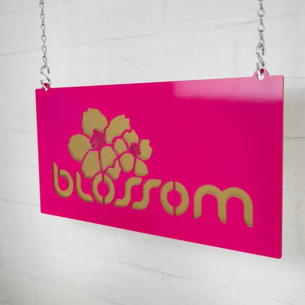 Pink decorative sign with gold floral design and text “Blossom” on white background, custom indoor or outdoor home décor accent