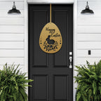 Gold Easter egg metal door sign on black door, white siding exterior with green plants, custom powder coated seasonal décor, farmhouse entry welcome accent sign