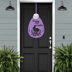 Black front door with purple Easter egg metal welcome sign, gray exterior wall and green plants, seasonal farmhouse décor, custom powder coated entry wall art sign