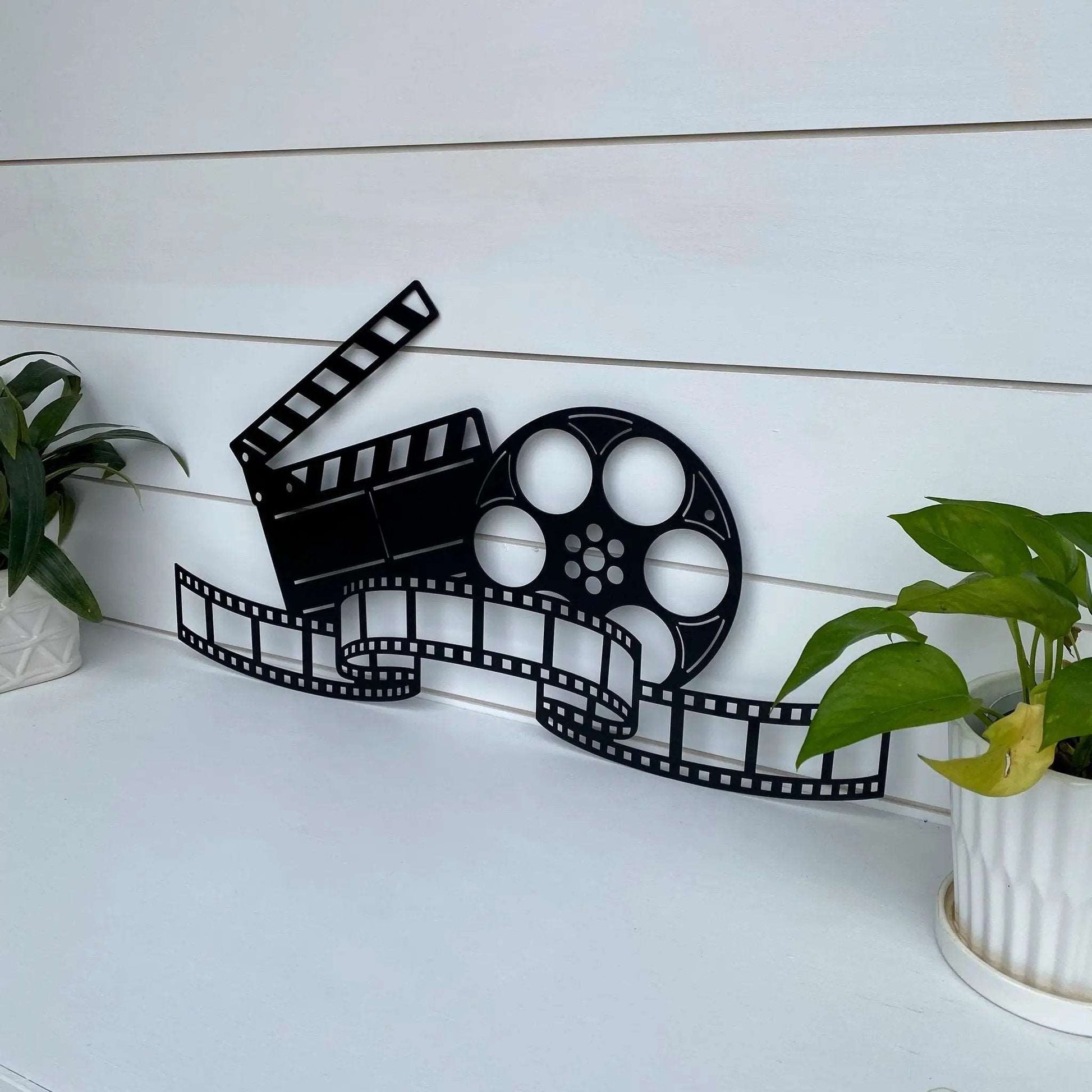 Hollywood-inspired metal wall art featuring movie reel, clapboard, and film strip design for cinematic spaces.