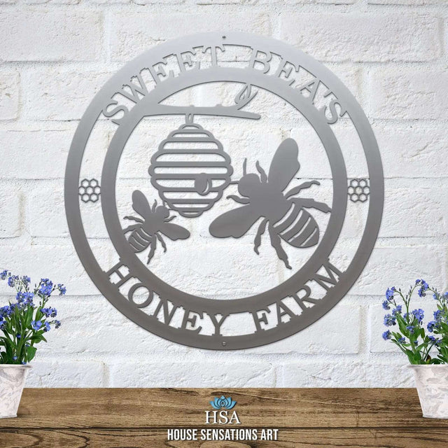 Polished chrome laser cut ranch sign with bee silhouettes, beehive, honeycomb accents, and “SWEET BEA'S HONEY FARM” text; rustic garden decor.