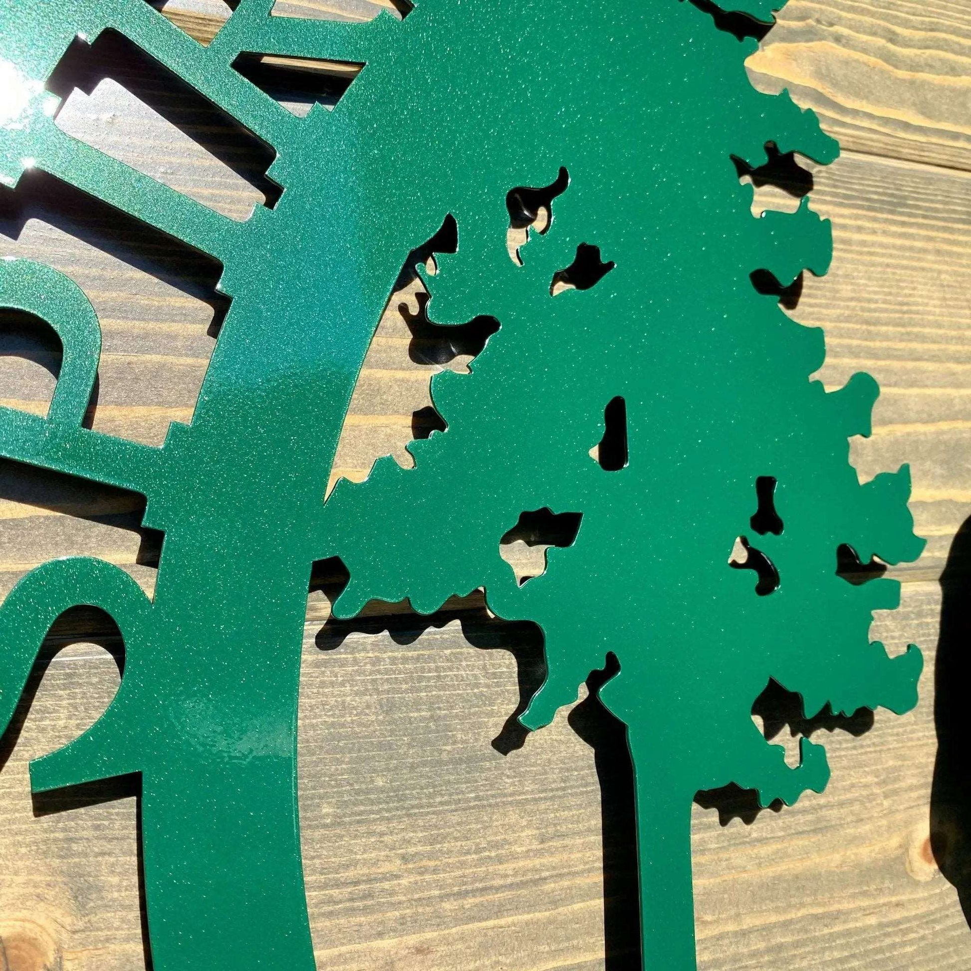 Close-up of emerald green custom horse tree sign laser cut details of horse under tree in glossy green metal.