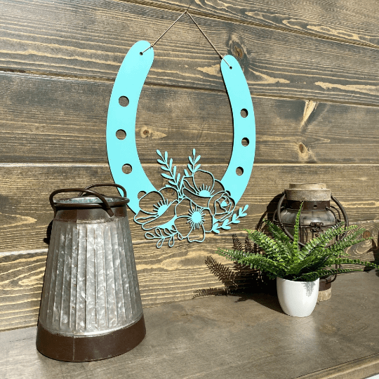 Decorative teal metal horseshoe with floral design on wood surface, rustic lucky home décor, farmhouse style wall art, gift horseshoe sign
