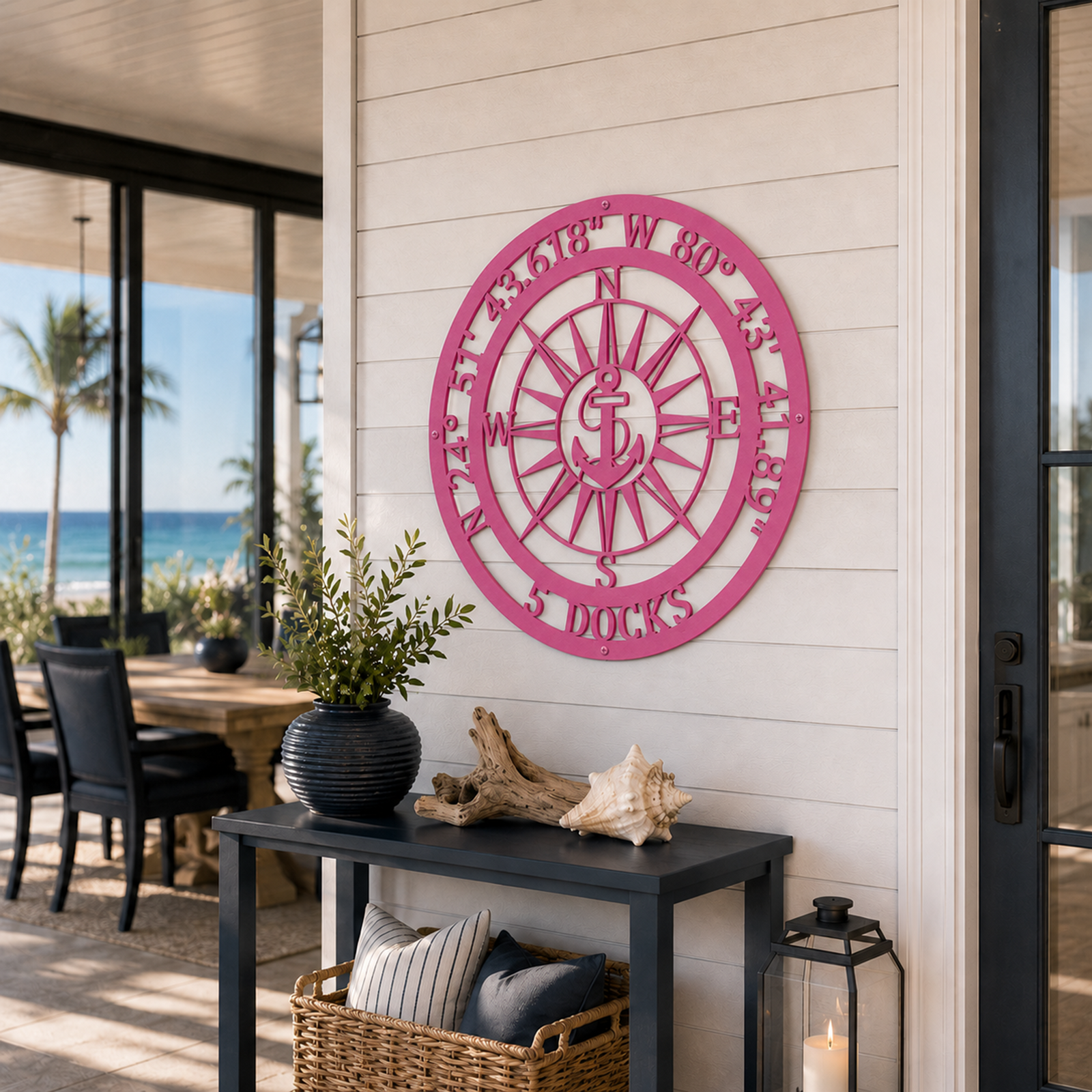 Hot pink finish of the custom coordinates anchor metal sign mounted above a black entryway console table in a bright coastal home hallway.