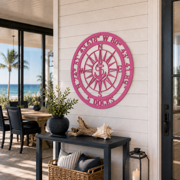 Hot pink finish of the custom coordinates anchor metal sign mounted above a black entryway console table in a bright coastal home hallway.