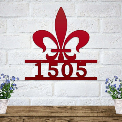 Fleur De Lis Address Sign with metal numbers on a white brick wall, featuring a lily design. Ideal for home décor and housewarming gifts, showcasing elegance and weather-resistant construction for outdoor use.