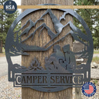 Round metal custom camper sign, trailer name plate RV decor with mountains, trees, lake, and a couple by a campfire.