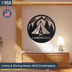 Round black metal camper sign with mountain and pine silhouette reading CAMPER VILLE, camping wall decor above a dresser.