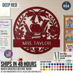 Introducing the Personalized Teacher Name Classroom Sign - a round custom metal sign shown in Deep Red displayed on a classroom wall. Features a beautiful collage of schoolbooks, teacher's apple, ruler, pencil in coffee mug, and ornate bow & flower, with personalized name plaque across the lower half. Featured photo reads Mrs. Taylor. Sign comes with color-matching screws and is available in more than 50 color finishes