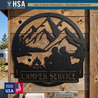 Personalized camper metal name sign, circular black frame with camping couple by a campfire, mountains and trees, RV decor.