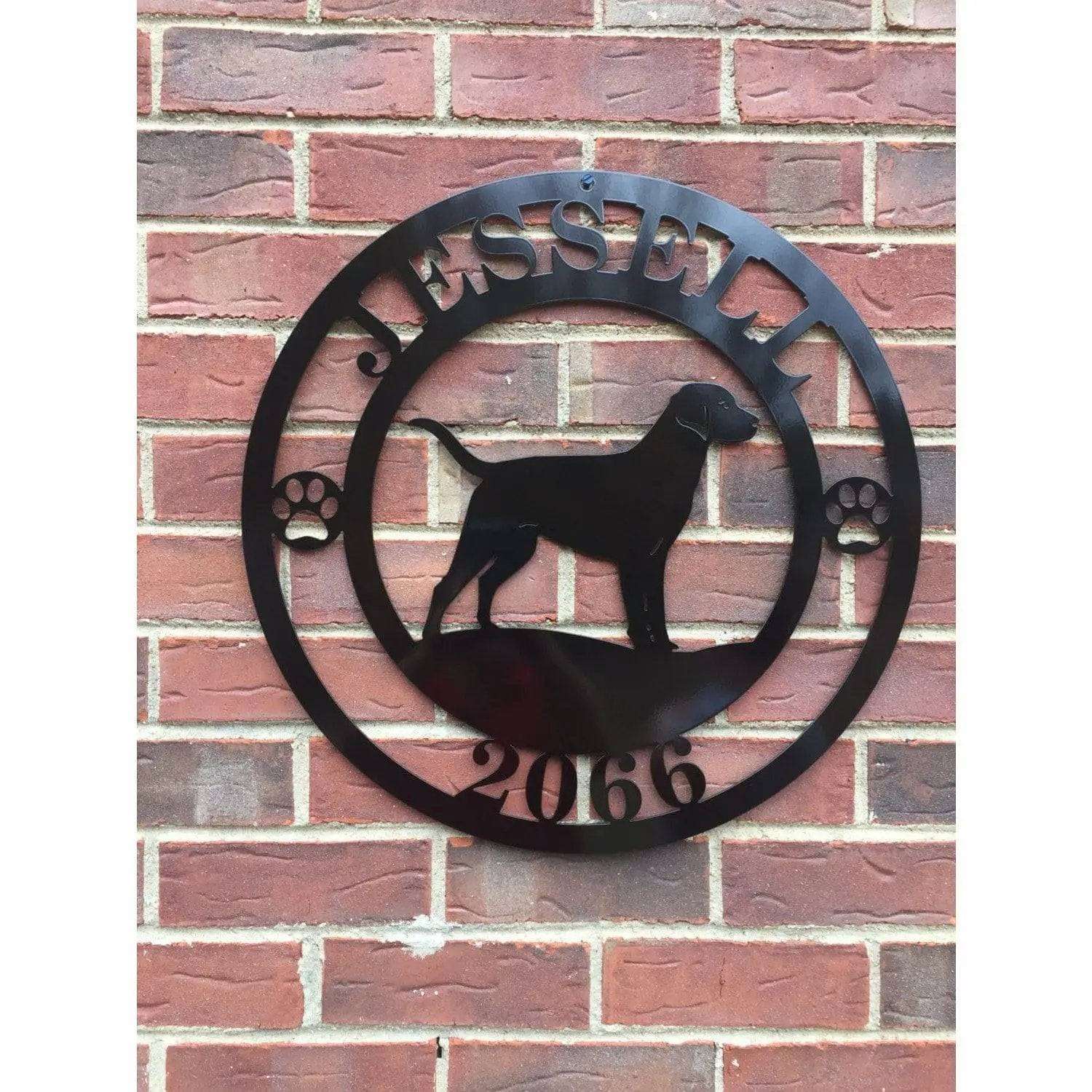 A black metal wall sign showing a Labrador dog silhouette standing, with “JESSELL,” “2066,” and paw prints on each side.