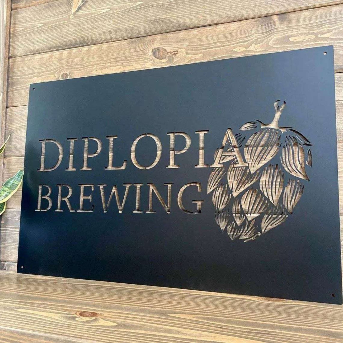 Large custom laser-cut metal business logo sign featuring “Diplopia Brewing” text and hop design on a wooden background, perfect for storefront or office wall décor – House Sensations Art.