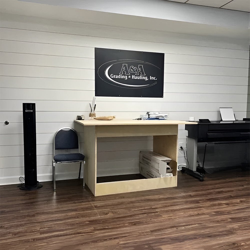Custom metal office and storefront sign featuring “A&A Grading & Hauling Inc.” logo, laser-cut steel wall décor in a small office space.