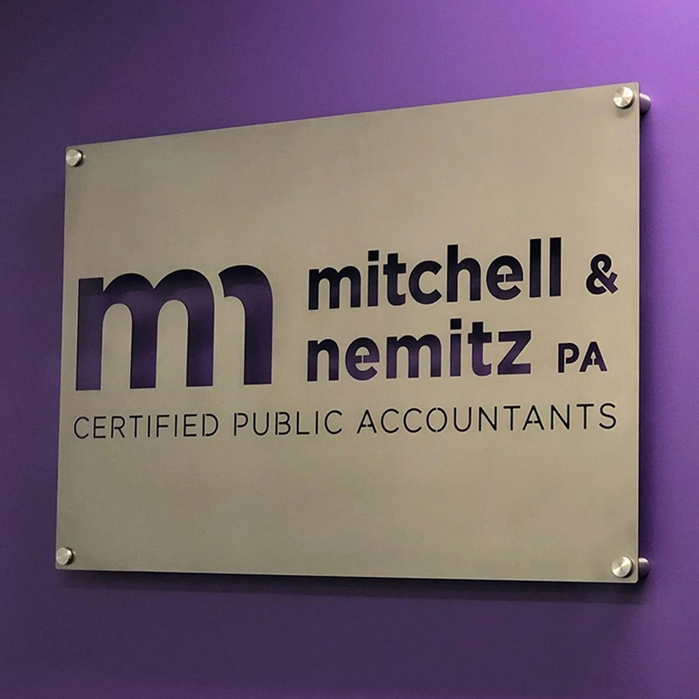 Custom metal office and storefront sign with laser-cut “Mitchell & Nemitz PA” logo, steel wall décor on vibrant purple backdrop.